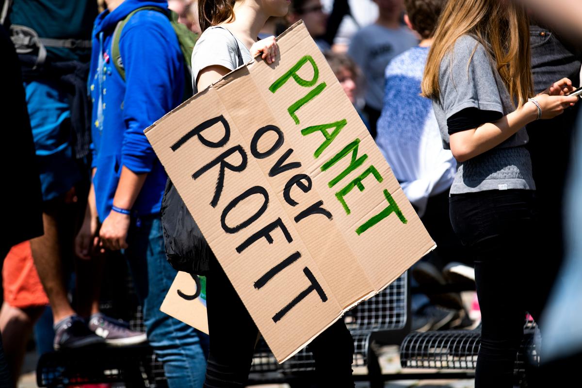 A large group of diverse climate activists marching and holding signs demanding action on climate change.