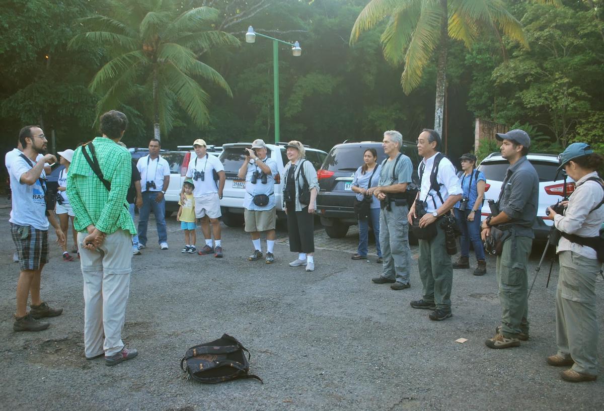 A community-based conservation education program, with people of various ages engaged in hands-on activities and discussions about wildlife protection.