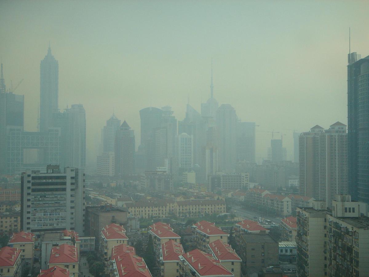 A city skyline obscured by a thick layer of smog due to an inversion event, trapping pollutants close to the ground